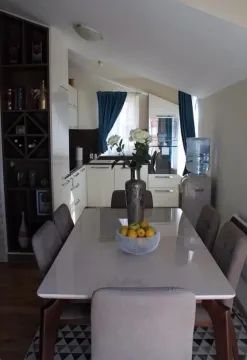 Dining area with a table, chairs, and shelving unit next to the kitchen. - image 4