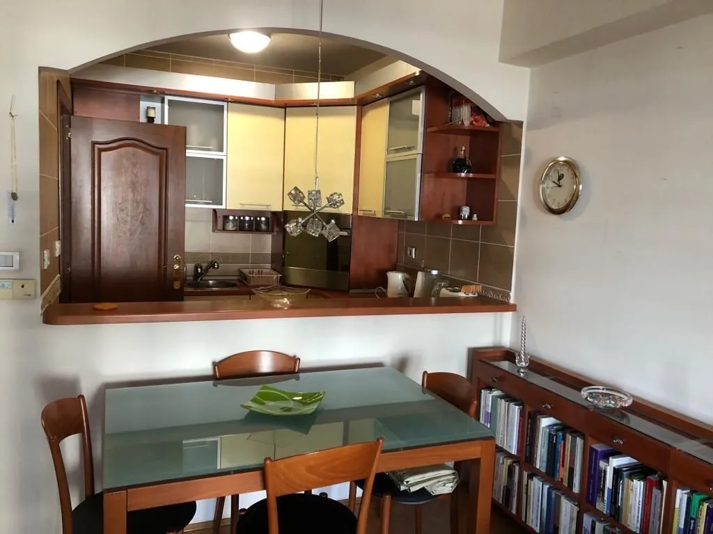 Dining table with chairs in front of a functional kitchen with a bar counter.