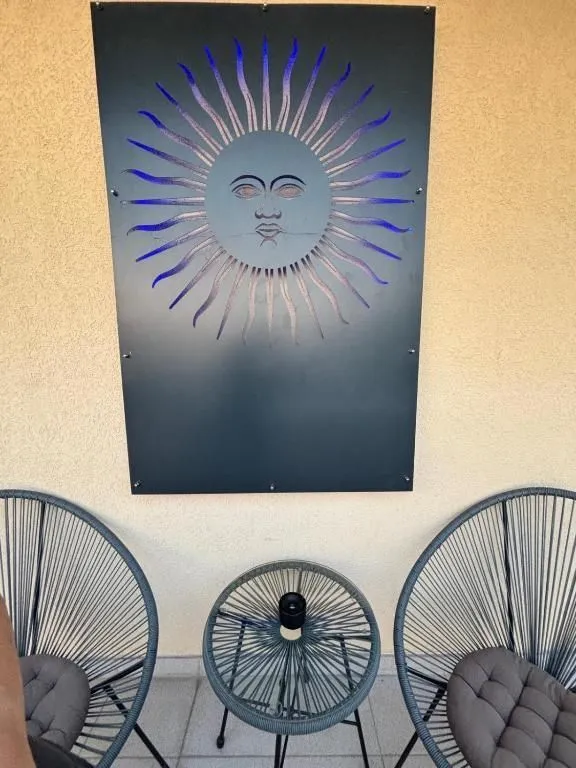 Manji balkon opremljen sa dvije stolice, stočićem i dekorativnim elementom na zidu.
