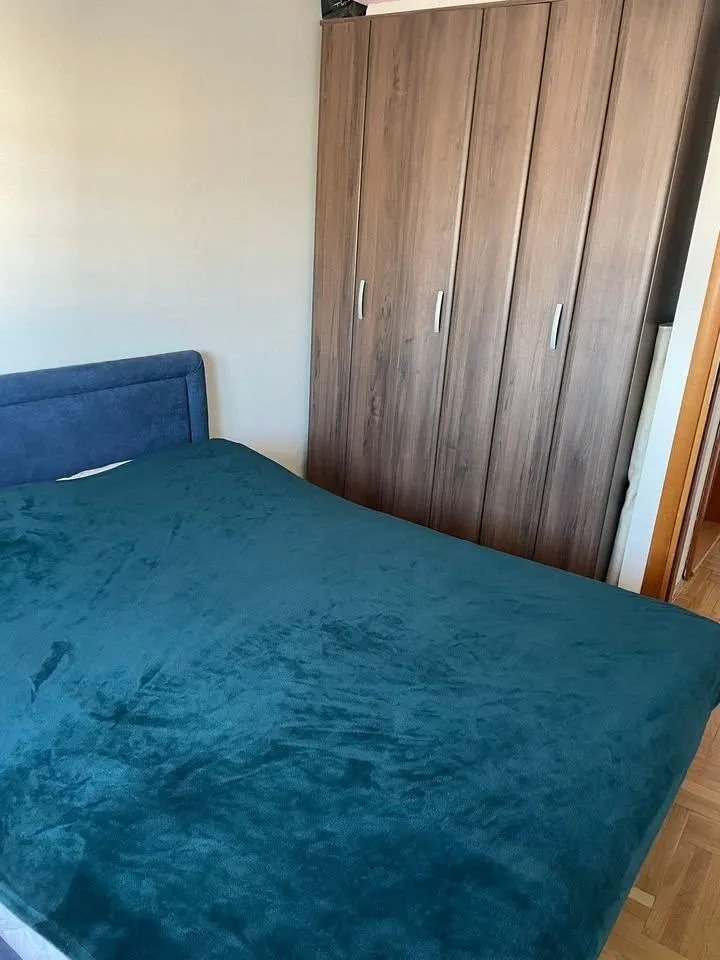 Spavaća soba sa bračnim krevetom i drvenim ormarom.