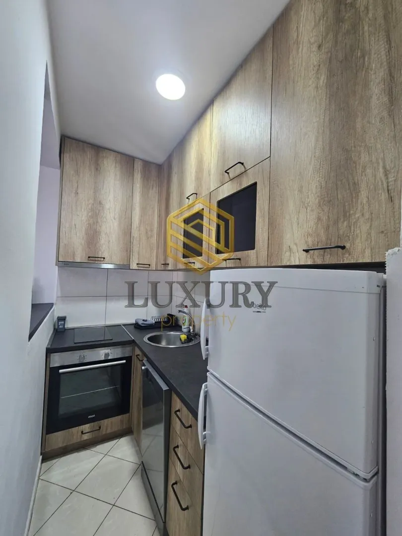 Smaller kitchen with wooden elements and a white refrigerator.