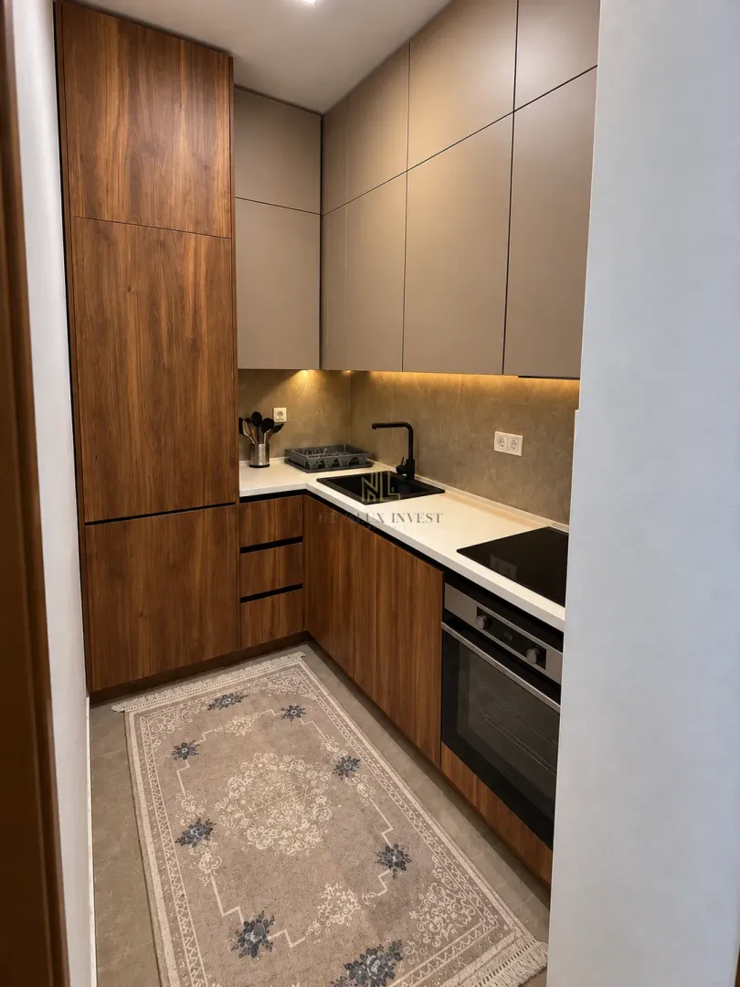 Modern kitchen with wooden elements, built-in oven, and sink.