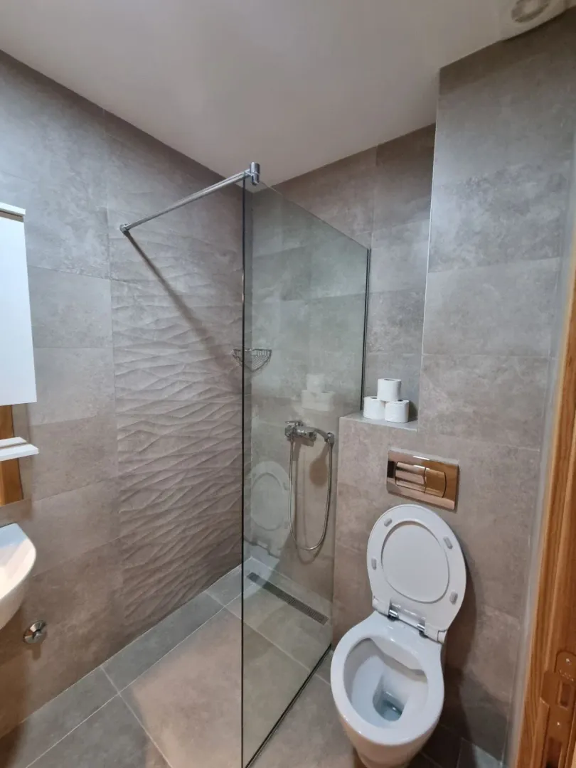 A modernly equipped bathroom with a walk-in shower and a wall-mounted toilet.