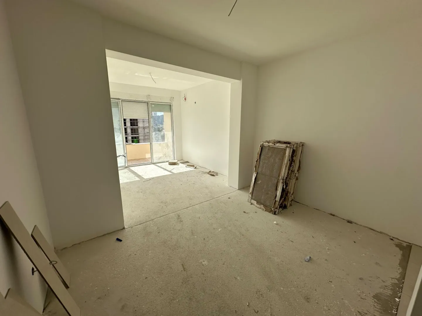 Empty room under construction with a view of the terrace and building materials.