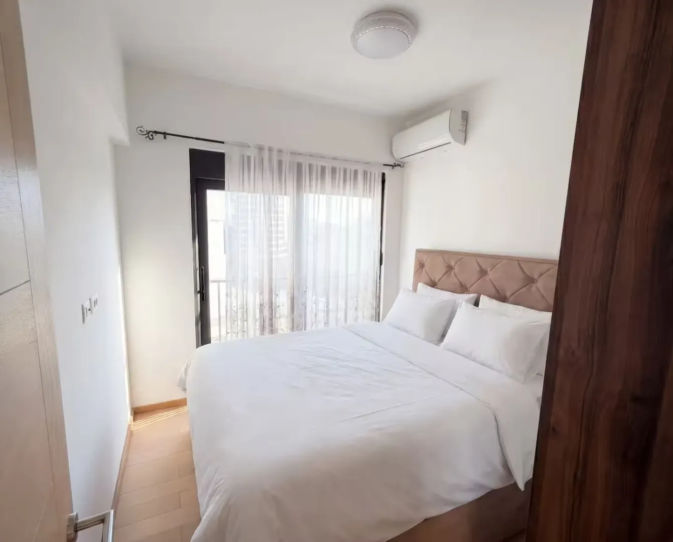 Namještena spavaća soba sa bračnim krevetom i izlazom na balkon.