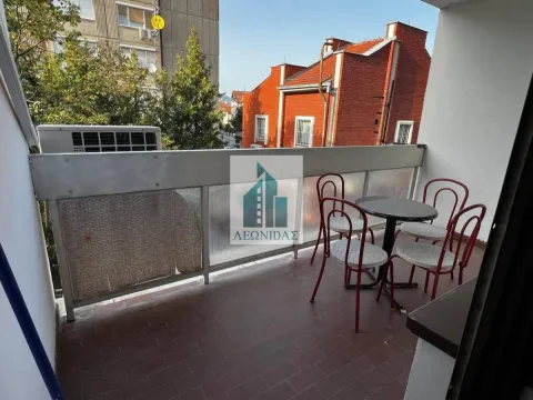 Small furnished balcony with a table and chairs and a view of surrounding buildings. - image 10