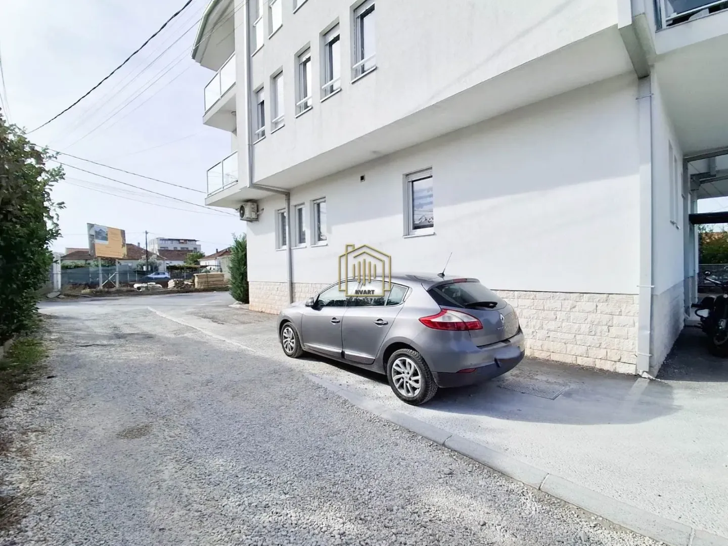 Pogled na spoljašnjost zgrade sa parking prostorom.