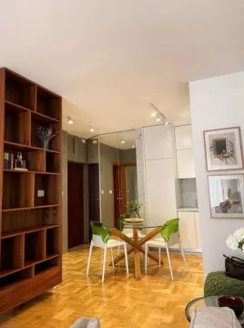 Living room with a dining area, parquet flooring, and a wooden bookshelf. - image 10