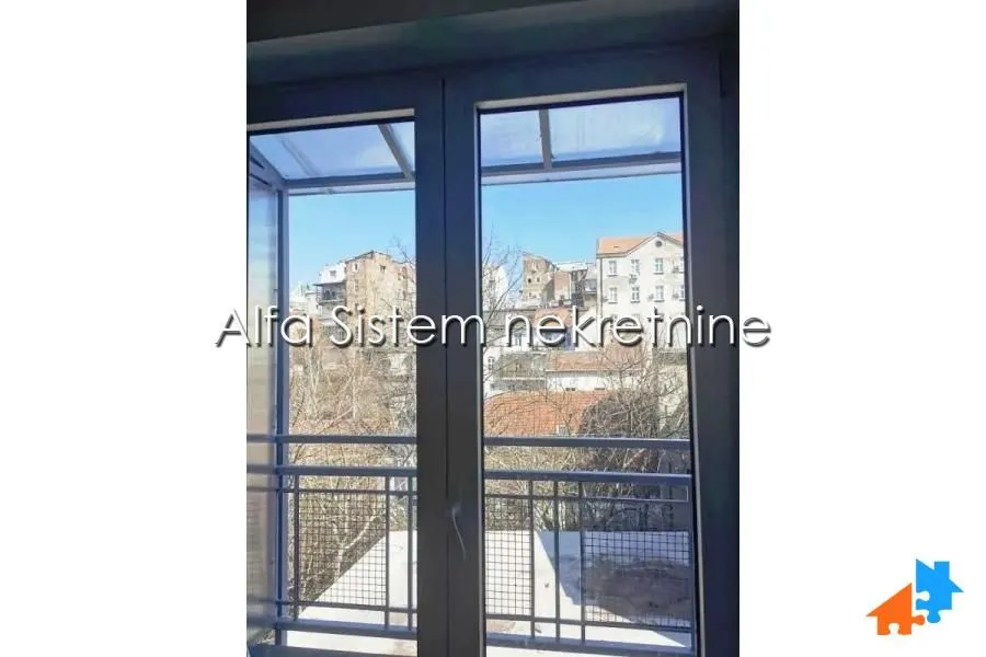Pogled kroz prozor na okolne zgrade i gradsku sredinu.
