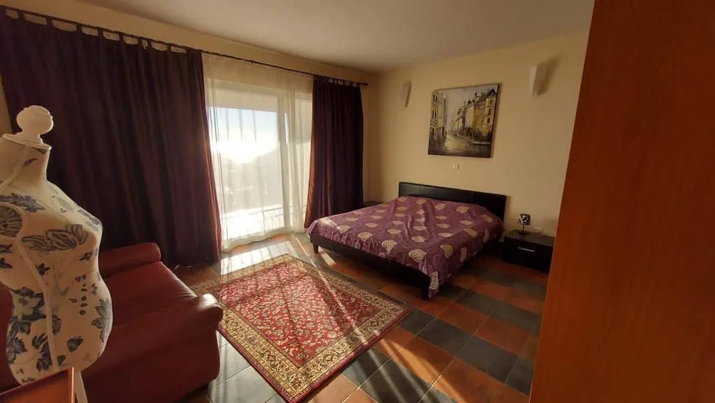Prostrana spavaća soba sa bračnim krevetom, crvenim tepihom i izlazom na terasu.