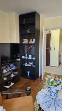 Living room with shelving units, a TV, and a view toward the entrance door. - image 3