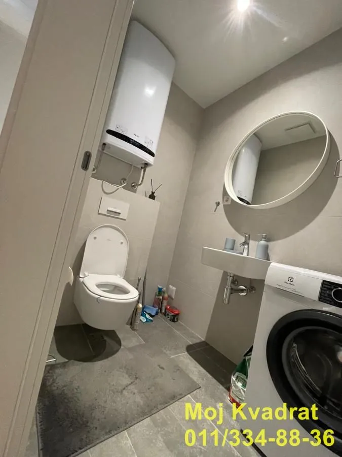 Small bathroom with a toilet, sink, and washing machine.
