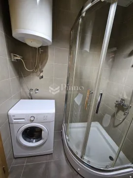 Smaller bathroom with a shower cabin, water heater, and washing machine. - image 9