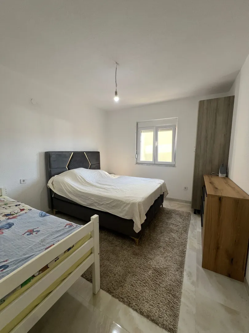 Bedroom with a double bed, single bed, wardrobe, and chest of drawers.