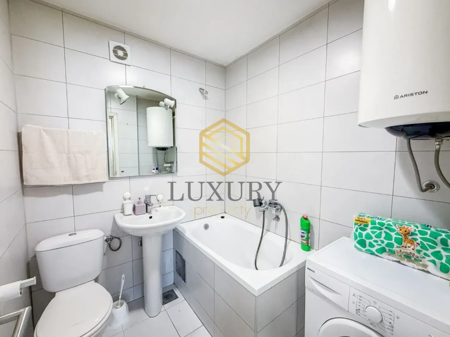Smaller bathroom with a bathtub, washbasin, toilet, and washing machine.