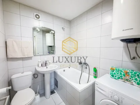 Smaller bathroom with a bathtub, washbasin, toilet, and washing machine. - image 7