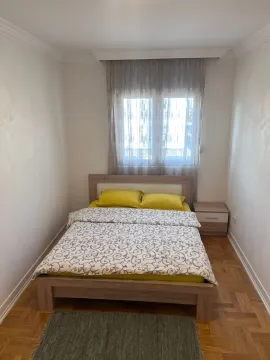 Manja spavaća soba sa bračnim krevetom, noćnim stočićem i prozorom. - image 11