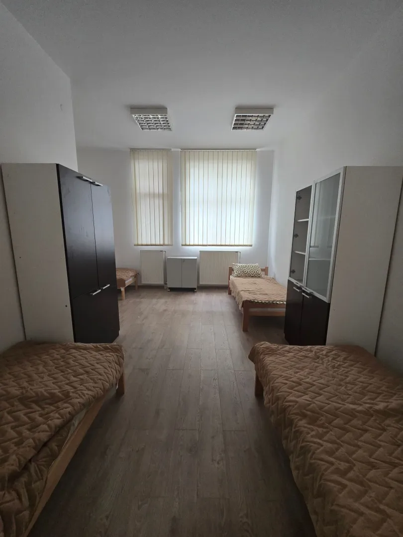 Prostrana spavaća soba sa više kreveta i ormarima.