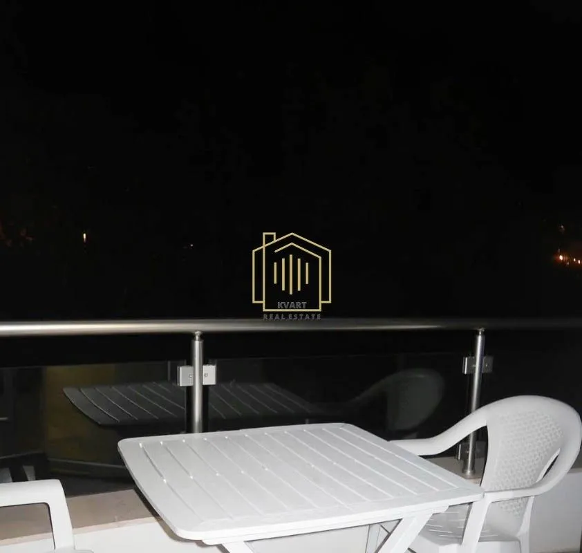 Terrace with a white plastic table and chairs at night.