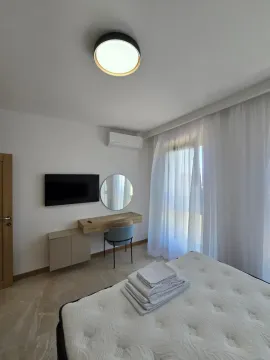 Spavaća soba sa krevetom, radnim stolom, televizorom i klima uređajem. - image 7