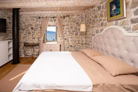 Rustic bedroom with stone walls and a sea view through the window. - image 9