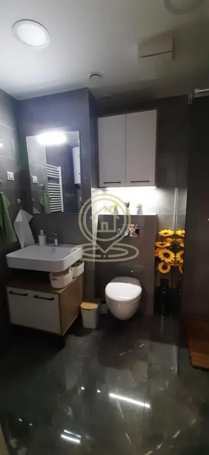 Savremeno opremljeno kupatilo sa umivaonikom, WC šoljom i zidnim ormarićem.