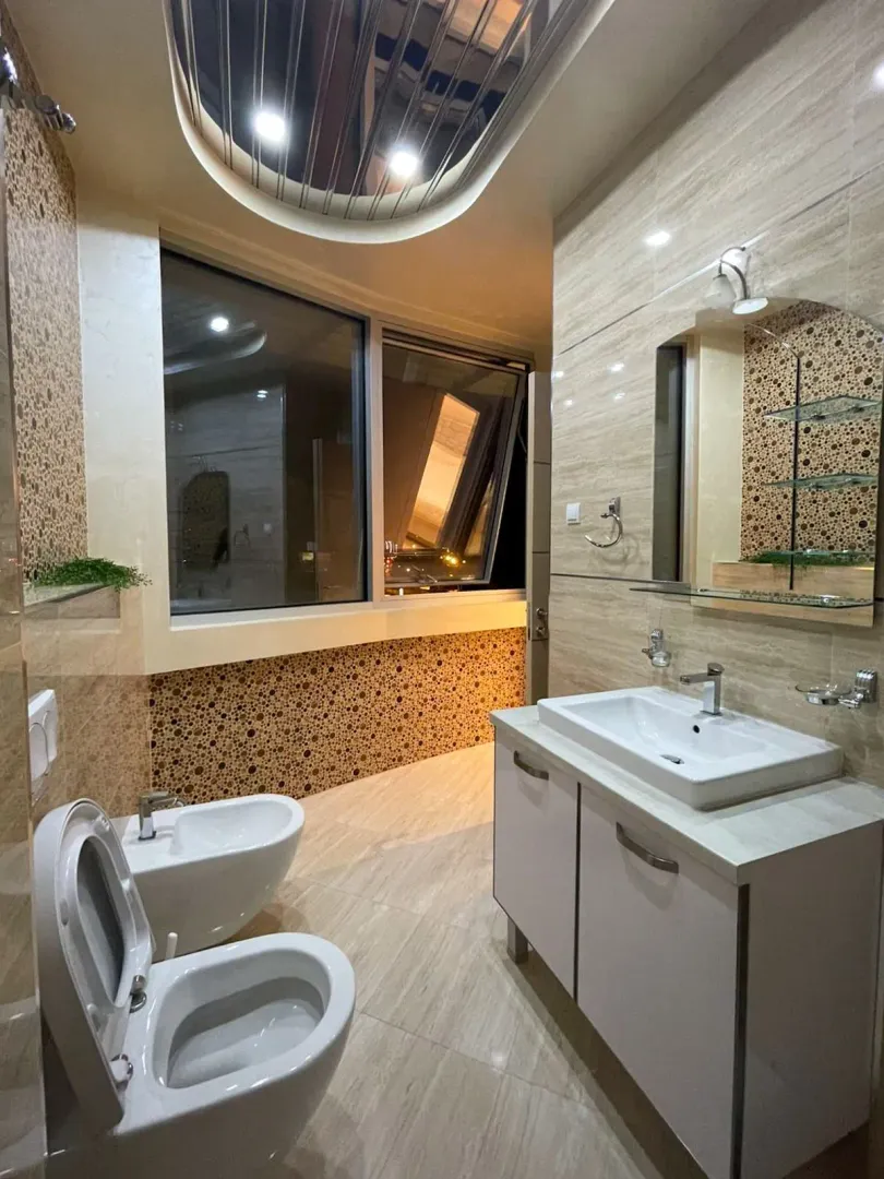 Moderno opremljeno kupatilo sa umivaonikom, WC šoljom, bideom i velikim prozorom.