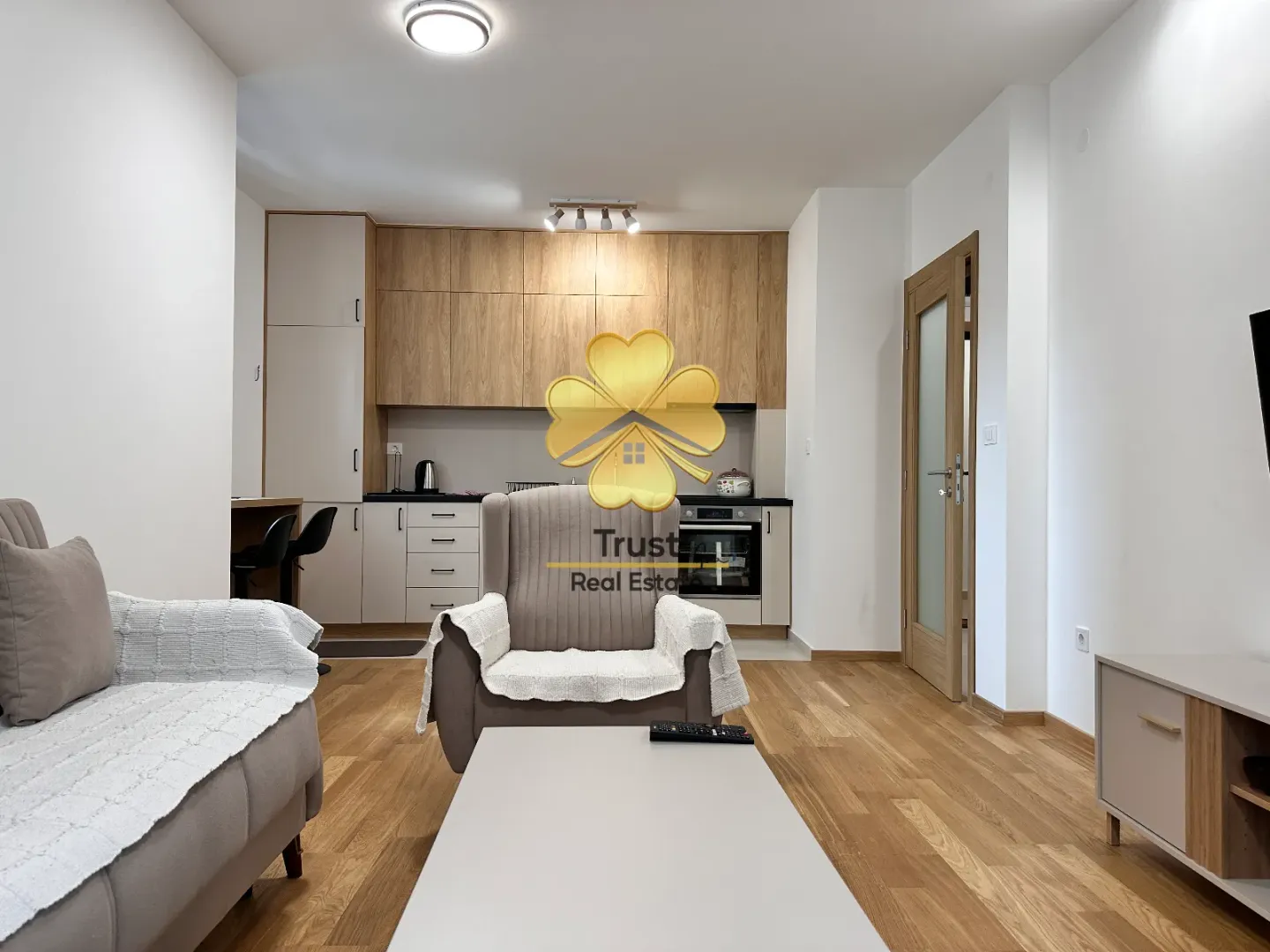 Living room with a sofa set and kitchen in the background.