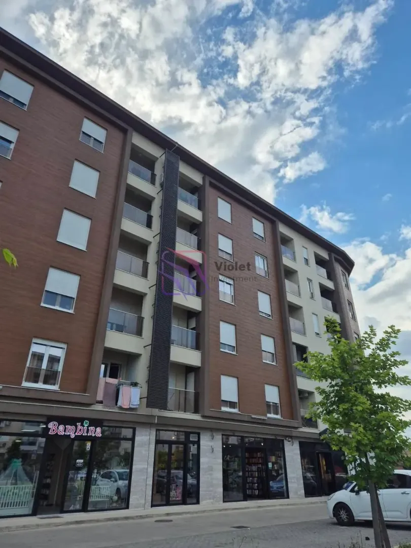 Pogled na spoljašnjost moderne stambene zgrade sa poslovnim prostorom u prizemlju.