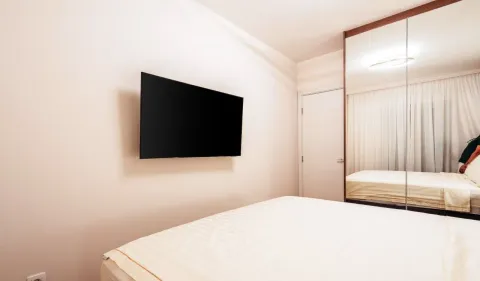 A view of the bed and wall-mounted TV in the bedroom. - image 7