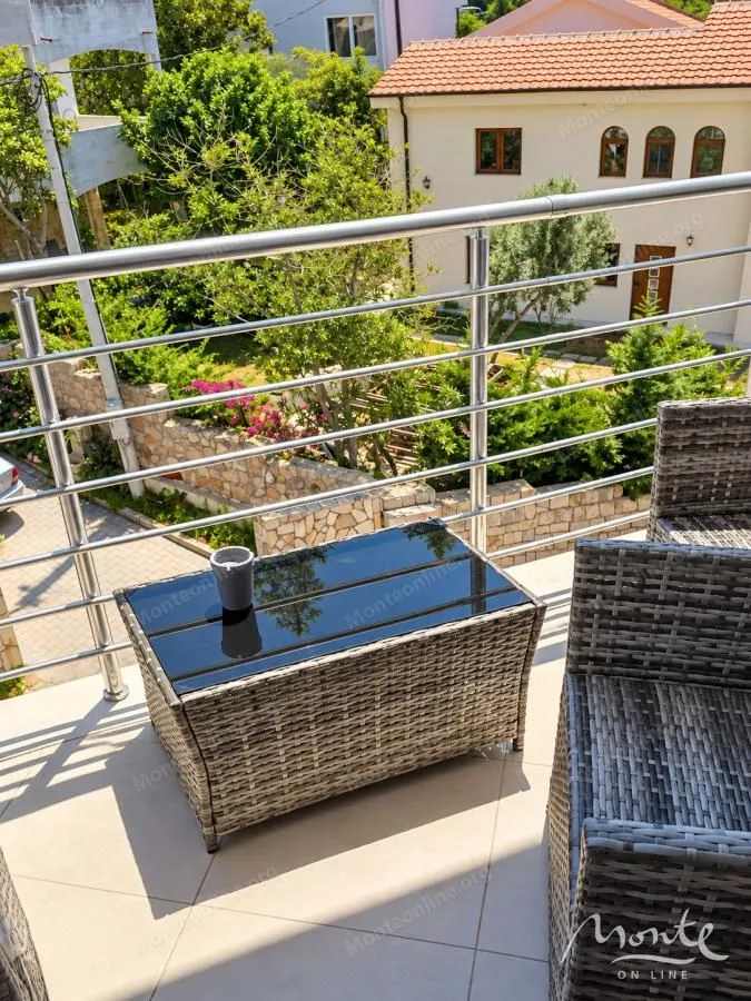 Namješten balkon sa garniturom za sjedenje i pogledom na dvorište i okolinu.