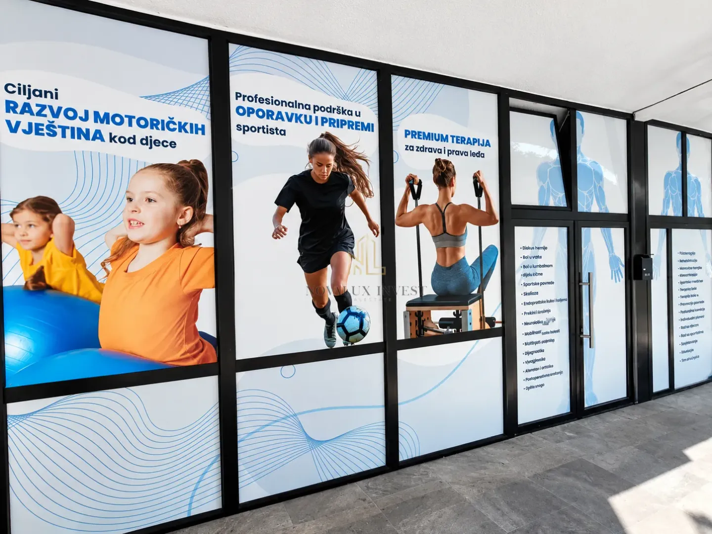 Commercial space facade with large glass shop windows and promotional stickers.