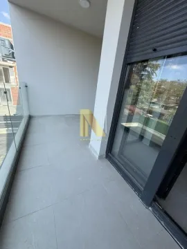 Prostrana popločana terasa sa staklenom ogradom i velikim balkonskim vratima. - image 11