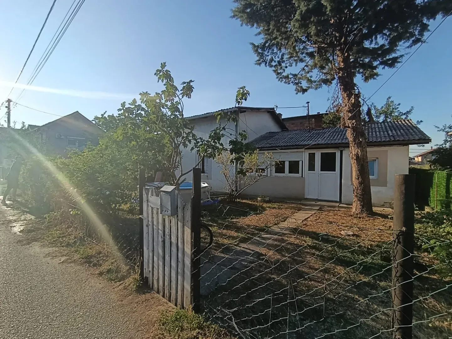 Pogled na dvorište i prizemnu kuću sa ogradom.