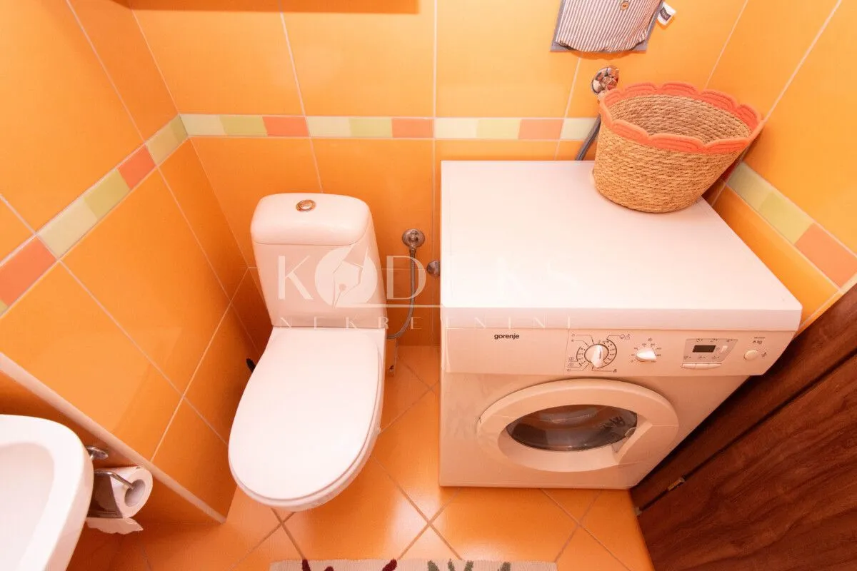 Manje kupatilo sa WC šoljom i veš mašinom.