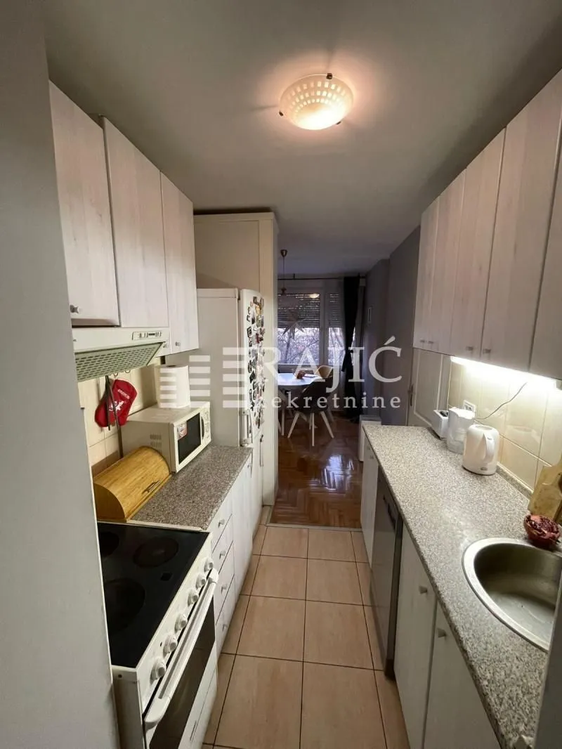 Small narrow kitchen with white cabinets and a stove.
