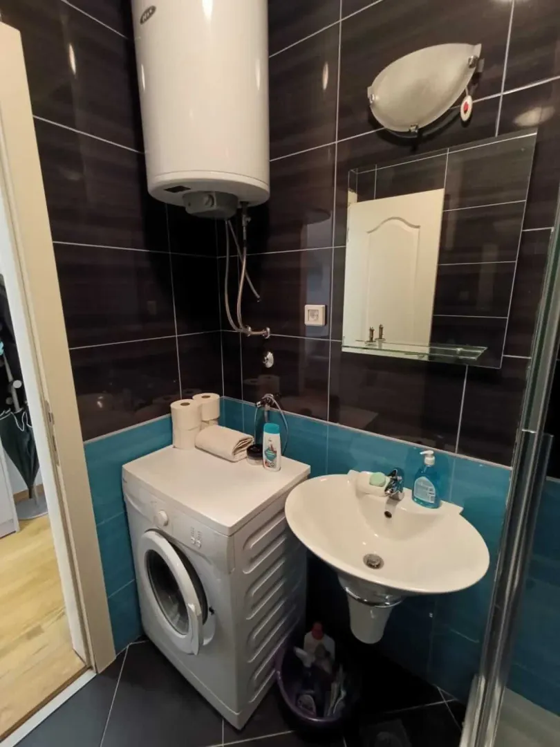 Bathroom with a washbasin, washing machine and a wall-mounted water heater.