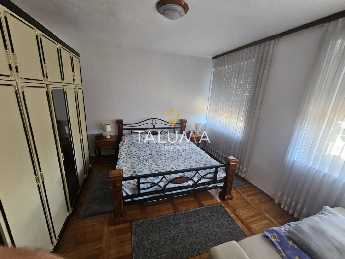 Furnished bedroom with a double bed, wardrobe, and wooden flooring.
