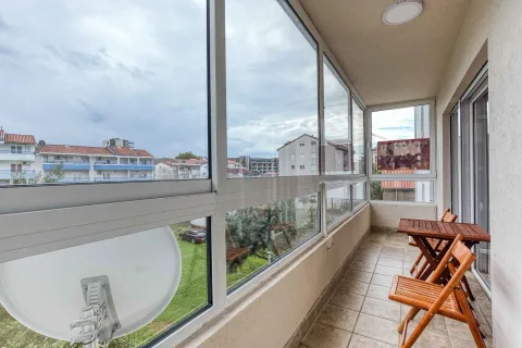 Enclosed balcony with a wooden table and chairs and a view of the neighborhood. - image 12