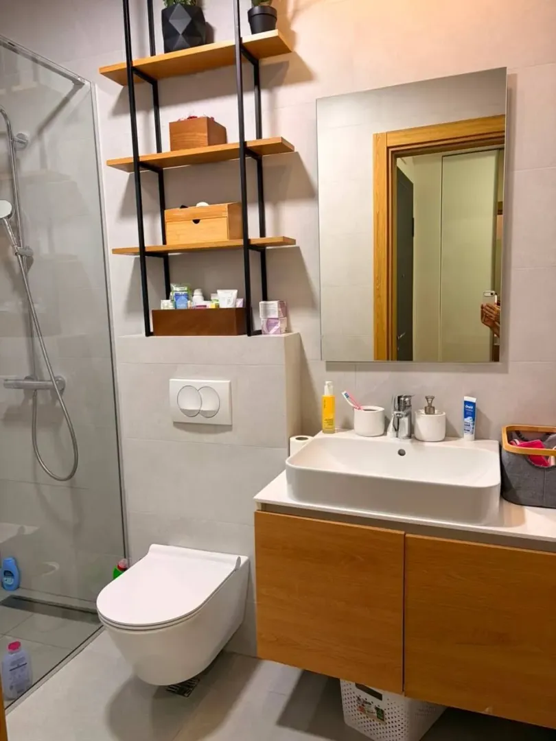 Moderno uređeno kupatilo sa tuš kabinom, umivaonikom i visećim toaletom.