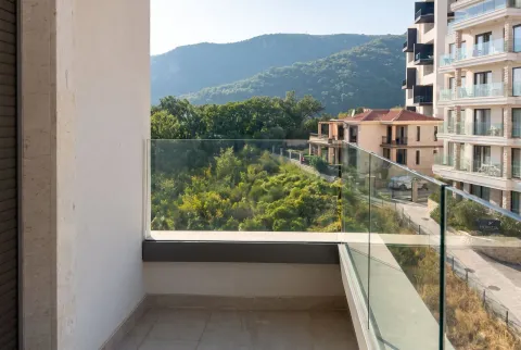 Moderan balkon sa staklenom ogradom i pogledom na zelenilo i okolne zgrade. - image 7