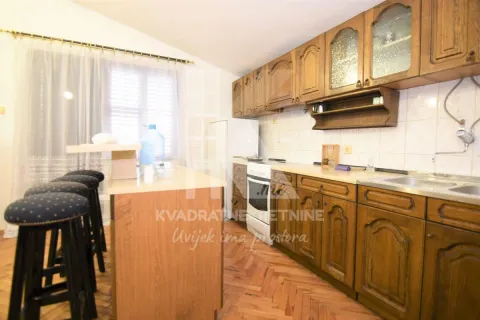 Kitchen equipped with wooden cabinets and a breakfast bar with bar stools. - image 3