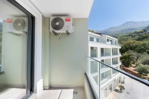 Manji svijetli balkon sa klima uređajem i pogledom na okolnu zgradu i brdo. - image 10