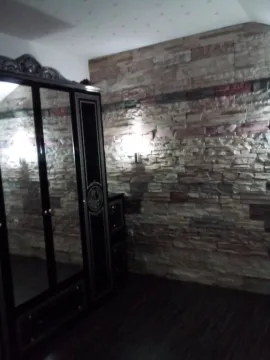 Part of a room featuring a decorative stone wall and a large dark wardrobe with mirrors. - image 3