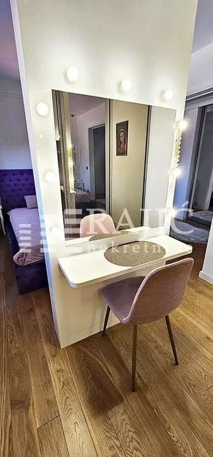 Bedroom with a bed and a vanity table featuring a mirror and light bulbs.