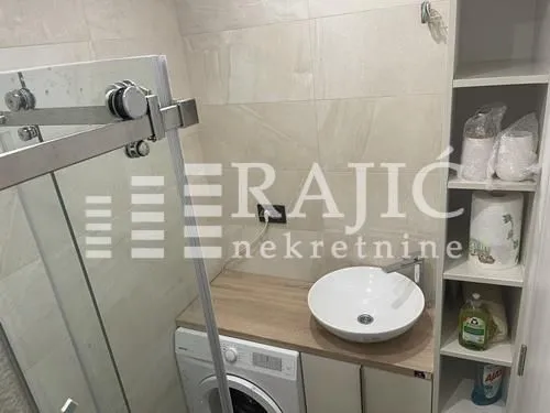 Small bathroom with a washbasin, washing machine, and storage shelves.