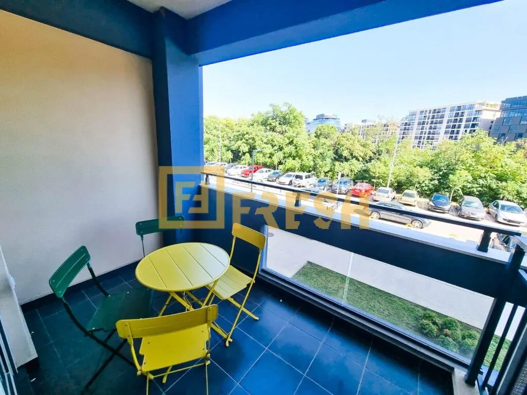 Natkriveni balkon sa garniturom za sjedenje i pogledom na parking i zelenilo.
