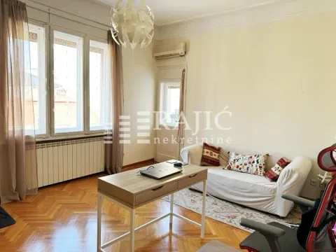 Living room with sofa, desk, and large windows. - image 9