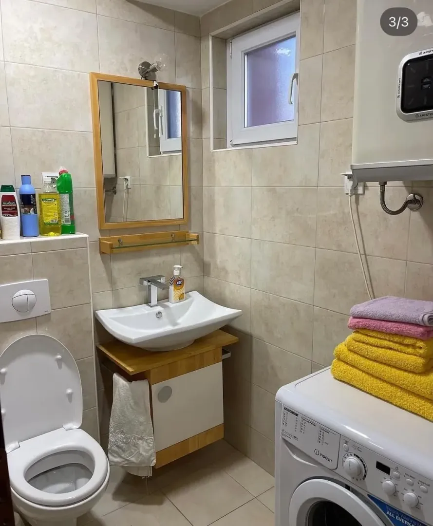 Smaller bathroom with a sink, toilet, washing machine, and shower.