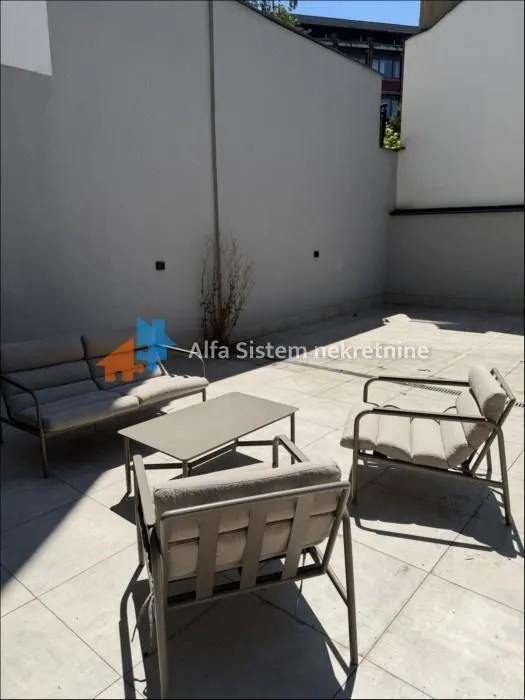 Popločana terasa sa garniturom za sedenje i stolom.
